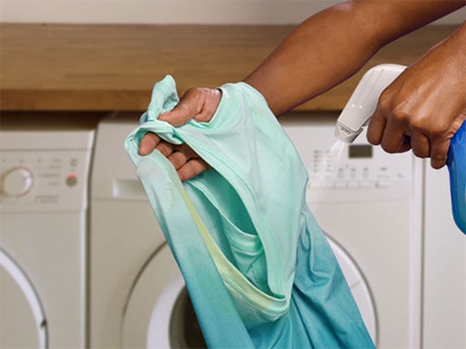 spraying smelly clothes with fabric sanitizer